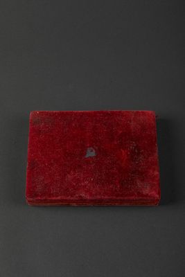 an old red box with a heart on it sitting on a black surface