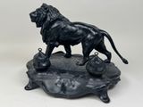 statue of a lion on a rock with a bell in its mouth