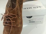 tan sued shoes with laces and a box on a white surface