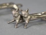 pair of silver cat cufflinks sitting on a gray surface