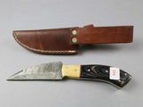 a knife that is sitting next to a leather sheath