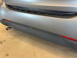 the rear end of a silver car with a red tail light