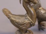two metal ducks that are standing on a pedestal