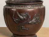a brown vase with a bird and flowers on it