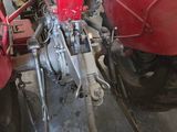 two red tractors parked in a garage with a man standing next to them