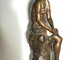 bronze statue of a boy sitting on a rock on a white background