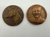 two bronze medallions depicting a man and a deer