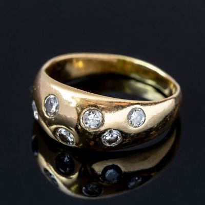 gros plan d'une bague en or avec des diamants sur une surface noire