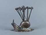 a silver sculpture of a snail on a table