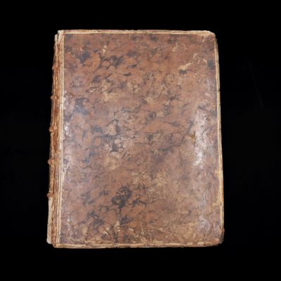 un vieux livre posé sur une table à côté d'un fond noir
