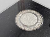 a silver coin sitting on top of a black surface