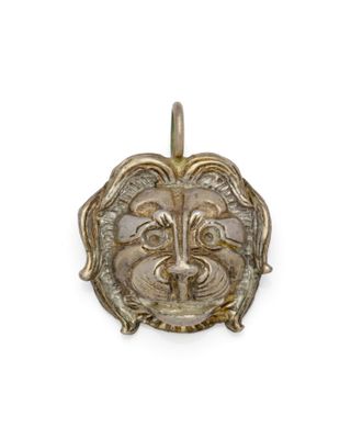 une image représentant un pendentif en forme de tête de lion dorée sur fond blanc
