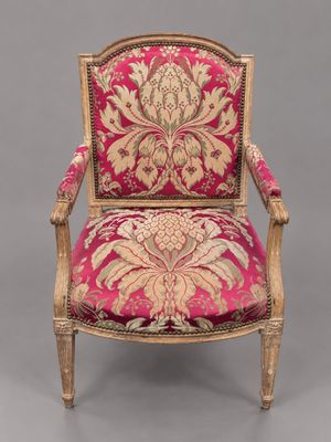 un fauteuil rembourré rose et doré, orné d'un motif floral