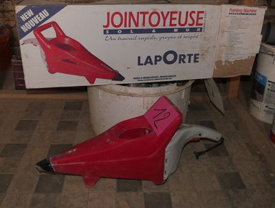a red blower sitting on the floor in front of a box