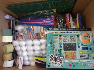a cardboard box filled with craft supplies and a lamp