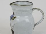 a white pitcher with a blue flower on it