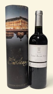 La bouteille de vin rouge se trouve à côté d'un carton.