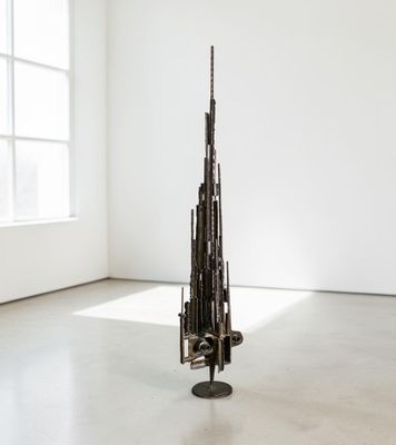 une sculpture représentant une tour, composée de tiges métalliques, dans une pièce