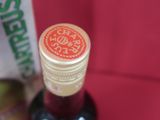 une bouteille de vin à côté d'une boîte posée sur une surface rouge