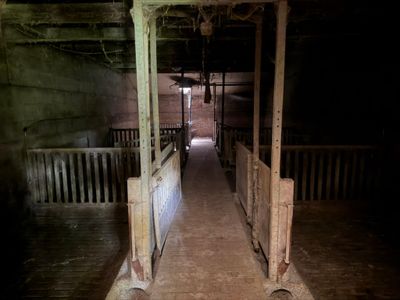 a long hallway leading to a barn with a wooden floor