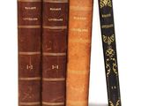 trois vieux livres sont empilés sur une surface blanche