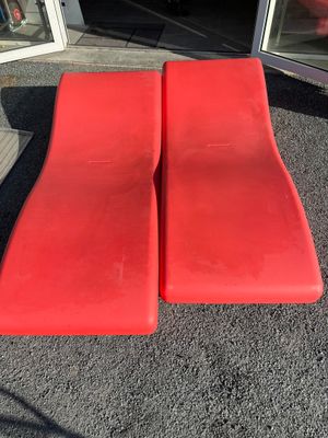 pair of red lounge chairs sitting in front of a glass door