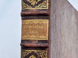an old book sitting on top of a wooden table next to a white wall