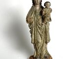 an old statue of a woman holding a child on a wooden base