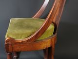 a wooden chair with a green seat and a black background
