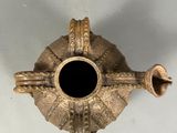 a gold vase with a black hole in the middle