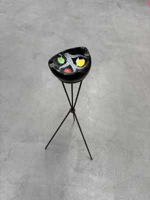 un tabouret noir posé sur un pied dans une pièce