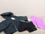 trois paires de shorts Nike et un sweat à capuche posés sur un lit