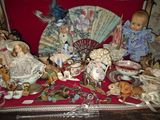 many dolls and figurines on a table with a fan