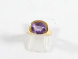 gros plan d'une bague en or avec une pierre violette