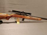 un fusil équipé d'une lunette de visée et d'un trépied, sur fond blanc