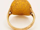 a close up of a gold ring with a coin on it