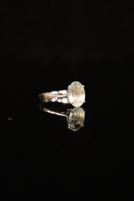a close up of a white diamond ring on a black surface