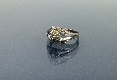 une image d'une bague en diamant posée sur une surface brillante