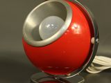 une lampe rouge posée sur un pied en métal