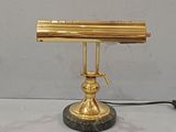 a gold desk lamp that is on top of a marble base