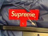 the jacket is blue and has a red supreme label on it