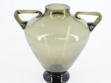 a glass vase with two handles on a white surface