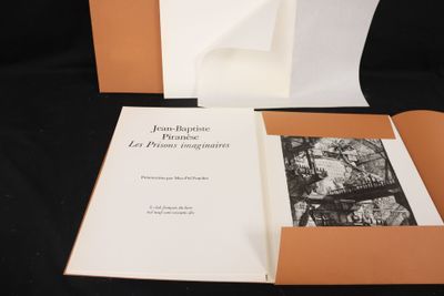 an open book sitting on top of a black table next to a black and white photo