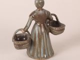 bronze figurine of a woman holding a basket of fruit