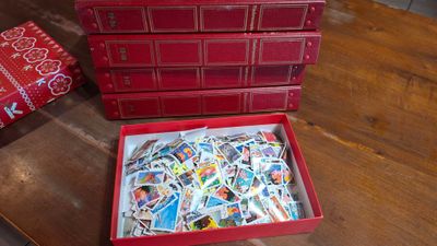 une boîte rouge remplie de timbres posée sur une table en bois