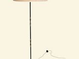 la lampe repose sur un pied en métal et est dotée d'un abat-jour beige
