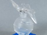 un vase en verre transparent avec un socle bleu posé sur une surface blanche