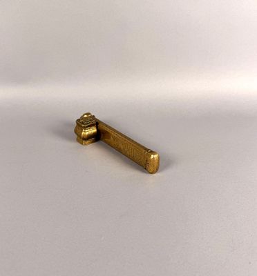 un petit objet en laiton posé sur une surface blanche