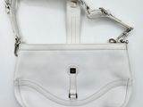 a white purse on a white surface with a metal clasp