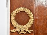 a wooden cabinet with a gold door handle and a wreath on the door